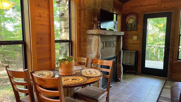 A wooden interior with a stone fireplace, a dining table with chairs, and large windows. - Secluded yet within minutes of your favorite outdoor activities!! (Marshall)