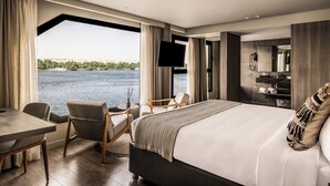 Una habitación de hotel moderna con una cama grande, un escritorio, una silla, un televisor y un baño con espejo y toallero.