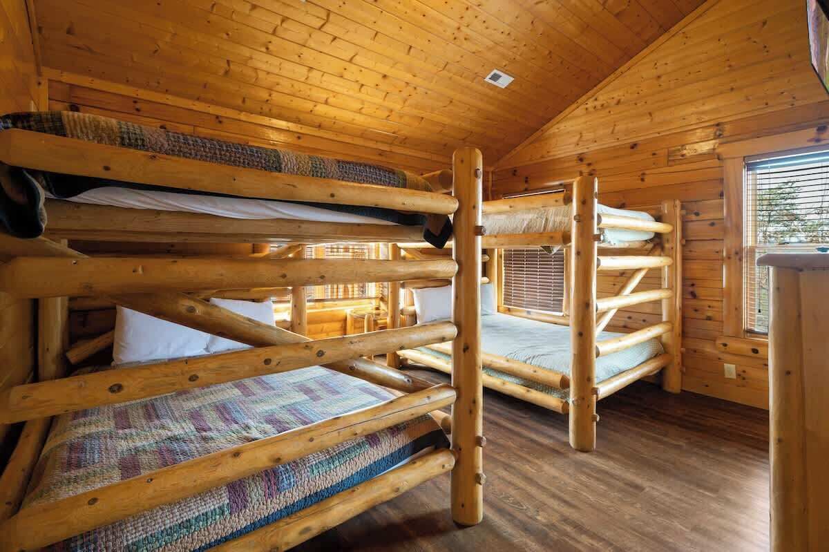 Una cabaña con literas, paredes de madera y una ventana.