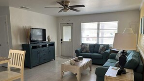 A living room with a television, a sofa, a coffee table, a lamp, and a ceiling fan. - Canal Suite with Water views (Saint James City)