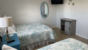 A bedroom with two beds, a TV, a lamp, and a small cabinet. - Canal Suite with Water views (Saint James City)