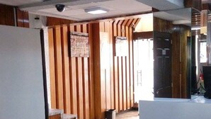 A hallway with a wooden wall, a white reception desk, and a tiled floor. - Hotel Patria (Mexico City)