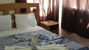 A hotel room with a bed, a wooden headboard, a nightstand, and a window with curtains. - Hotel Patria (Mexico City)