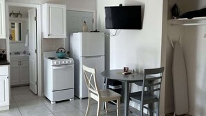 Eine kleine Küche mit Herd, Kühlschrank und einer Essecke mit Tisch und Stühlen.