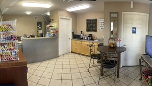 A kitchen with a microwave, coffee maker, and a dining area with a table and chairs. - Best Budget Inn (Bastrop)