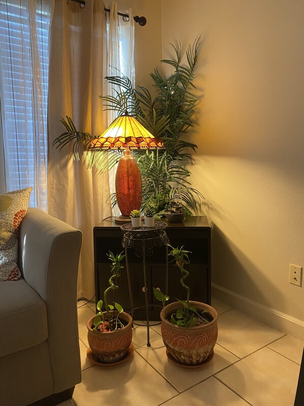 Relax in this inviting space with a comfortable sofa, decorative lamp, and lush greenery.