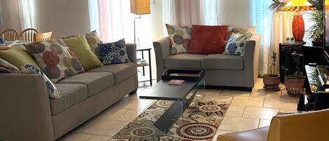 A living room with a sofa, armchair, coffee table, and a ceiling fan.