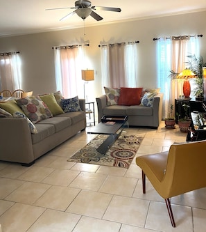 A living room with a sofa, armchair, coffee table, and a ceiling fan.