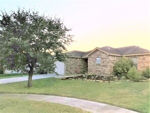 Set amidst a lush lawn, this charming property features a gabled roof and a mature tree.
