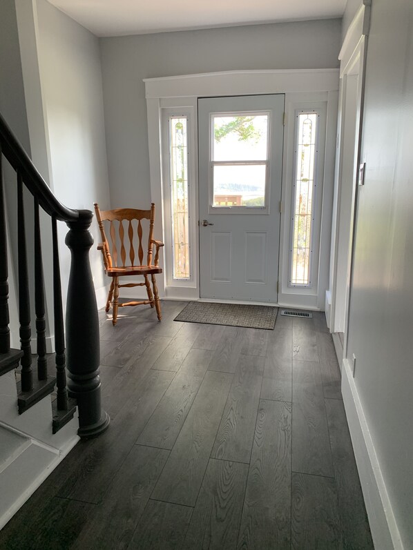 A hallway with a wooden chair, a white door, and a staircase.