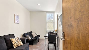 A room with a black sofa, a small table, and a wooden door.