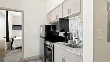 A compact kitchen with a refrigerator, stove, microwave, and sink.