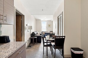 A modern kitchen with granite countertops, a wooden door, and a dining area with a table and chairs. - Downtown Historic Warehouse District Lofts 203 (Cleveland)