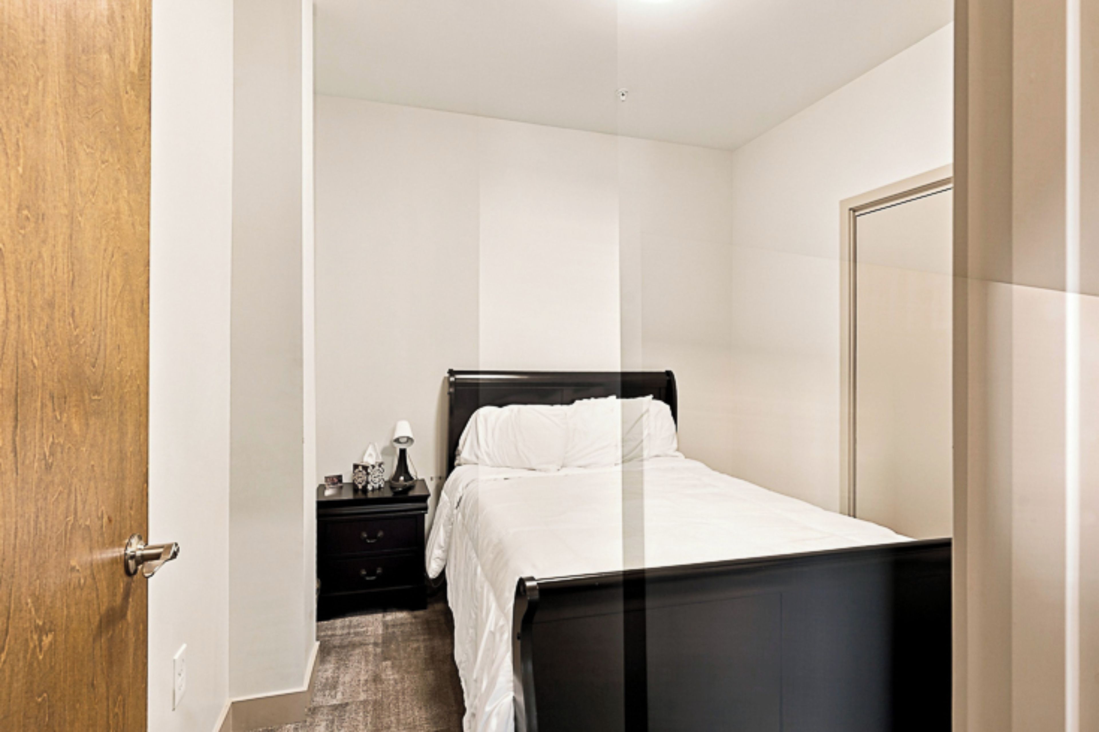 A bedroom with a bed, a nightstand, and a door.