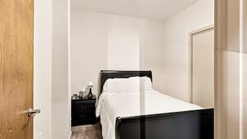 A bedroom with a bed, a nightstand, and a door.