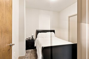 A bedroom with a bed, a nightstand, and a door.