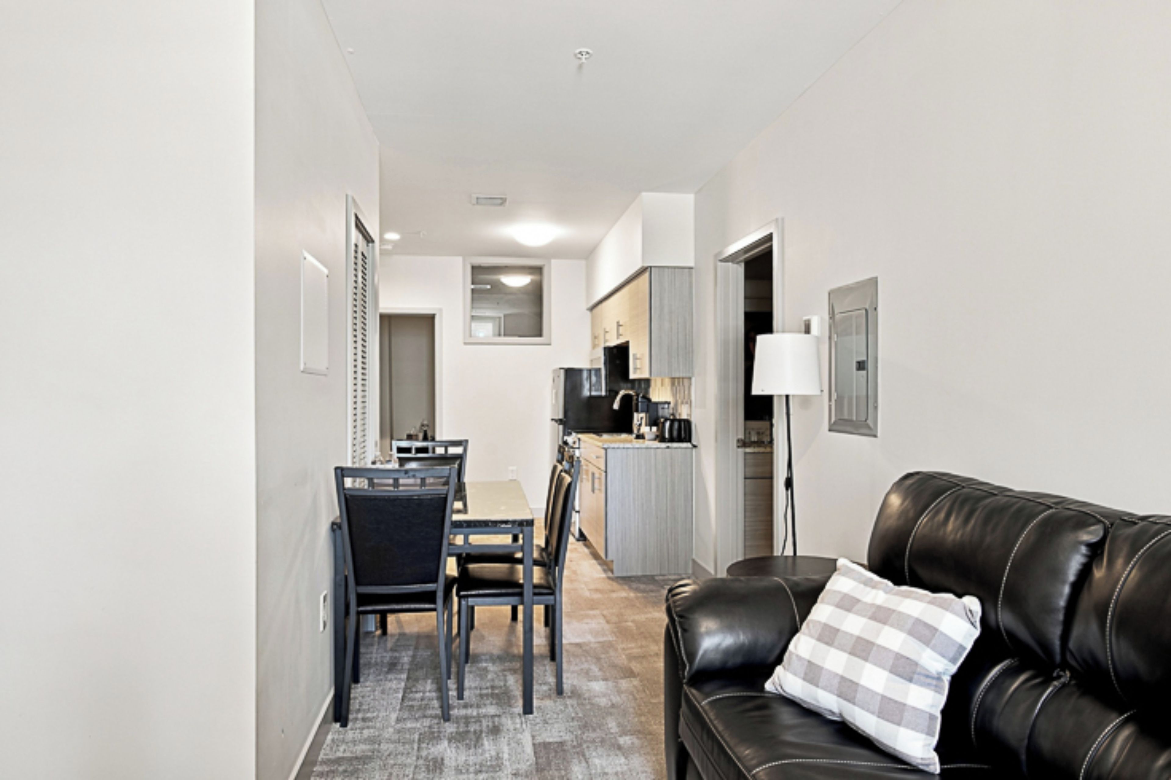 A modern living room with a leather sofa and a dining area with a table and chairs.