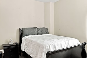 A bedroom with a single bed, a nightstand, and a bedside table.