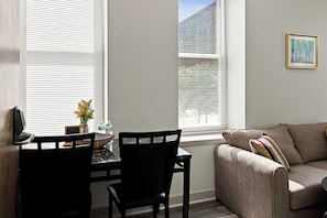 A living room with a sofa, a dining table with chairs, and a window with blinds. - Downtown Historic Warehouse District Lofts 207 (Cleveland)
