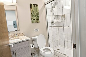 A bathroom with a toilet, sink, and shower. - Downtown Historic Warehouse District Lofts 309 (Cleveland)