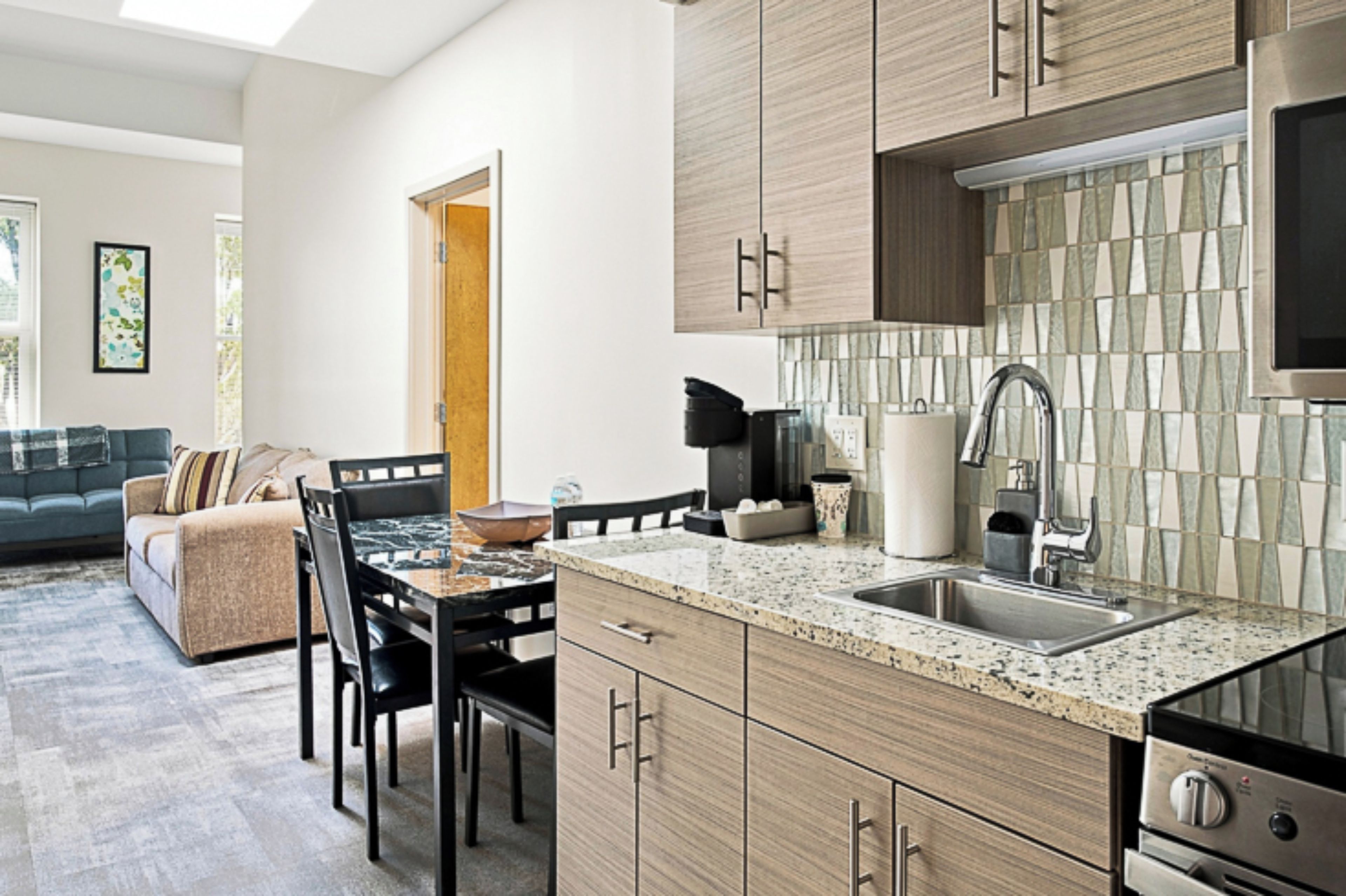 A modern kitchen with granite countertops, stainless steel appliances, and wooden cabinetry.