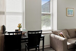 A living room with a sofa, a dining table with chairs, and a window with blinds. - Downtown Historic Warehouse District Lofts 307 (Cleveland)