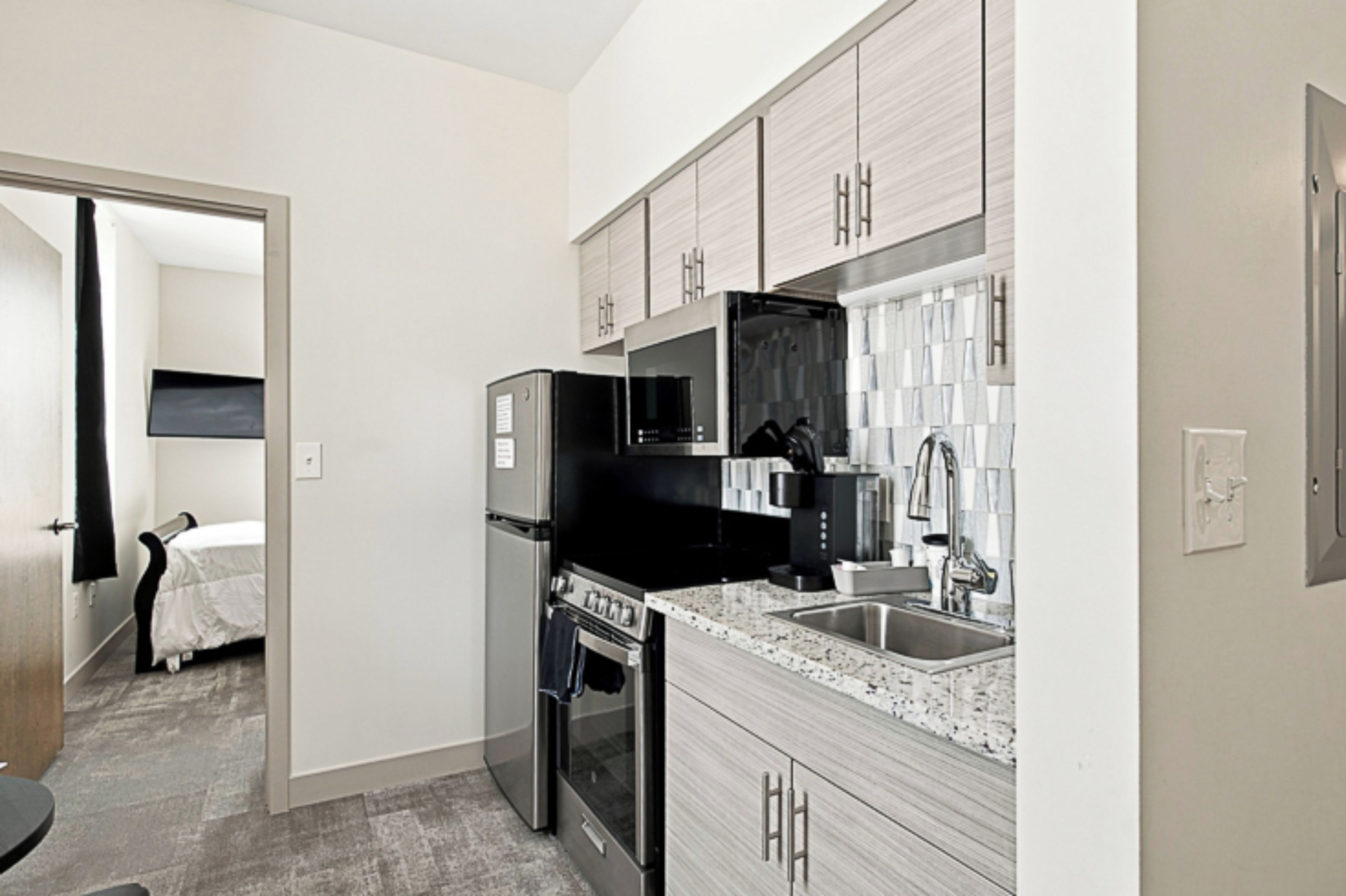A compact kitchen with a refrigerator, stove, microwave, and sink.