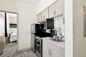 A compact kitchen with a refrigerator, stove, microwave, and sink.