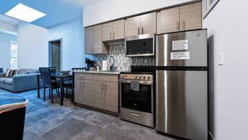 A modern kitchen with stainless steel appliances, wooden cabinets, and a tiled backsplash.