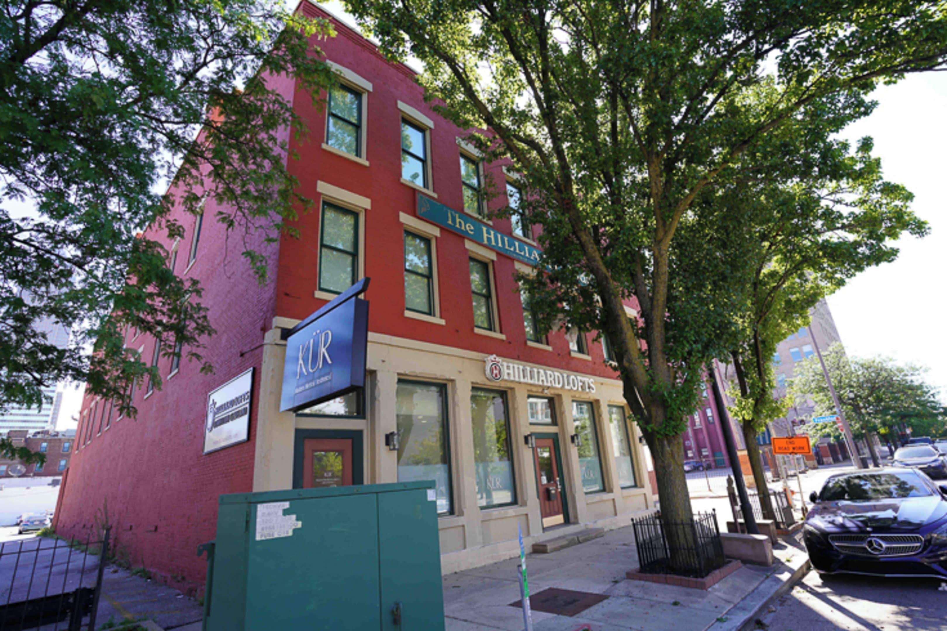 A red brick building with a storefront named 'HILLIARD LOFTS' and a sign for 'KUR' above it.