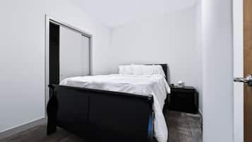 A bedroom with a bed, a nightstand, and a door.