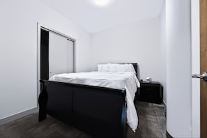 A bedroom with a bed, a nightstand, and a door. - Downtown Historic Warehouse District Lofts 209 (Cleveland)