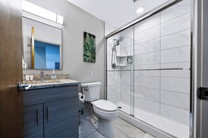 A modern bathroom with a shower, toilet, and vanity. - Downtown Historic Warehouse District Lofts 209 (Cleveland)