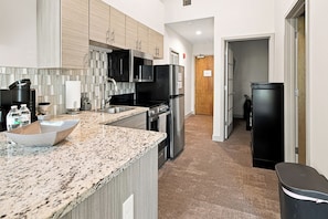 A modern kitchen with granite countertops, stainless steel appliances, and a tiled backsplash.