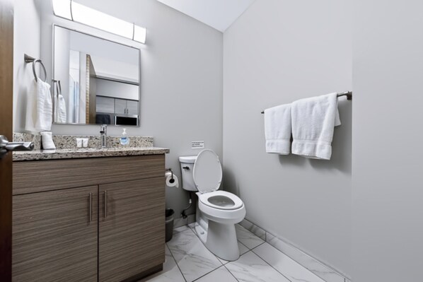 A modern bathroom with a toilet, sink, and vanity.