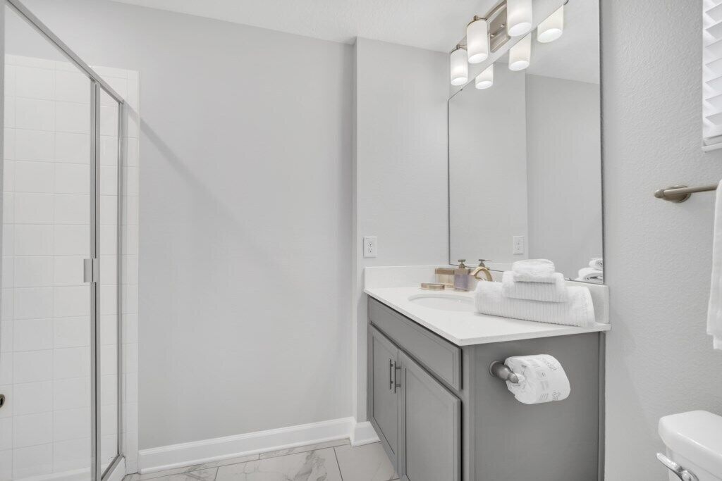 Une salle de bain moderne avec une douche à parois de verre, un meuble-lavabo avec un miroir et des toilettes.