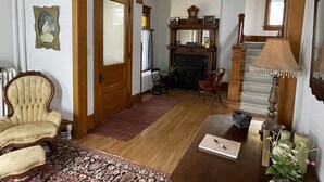 Un salon traditionnel avec un fauteuil en bois, une cheminée, un escalier et un coin repas.