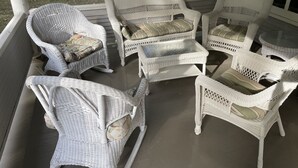 Un espace extérieur aménagé, abrité et doté de mobilier en osier et de chaises rembourrées.