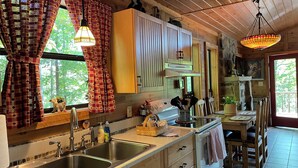 Une cuisine chaleureuse dans un chalet, avec des meubles en bois, un grand évier et un coin repas comprenant une table et des chaises.