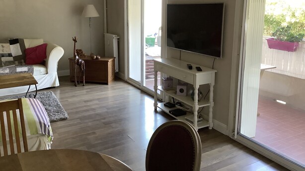 Una sala de estar con televisor de pantalla plana, un sofá, una mesa de centro y una lámpara.