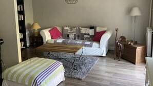 Una sala de estar con sofá, mesa de centro, estantería y lámpara.