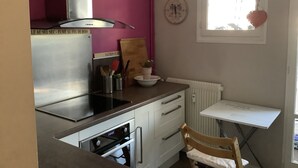 Una cocina compacta con horno integrado, microondas y una pequeña ventana decorada con un corazón.