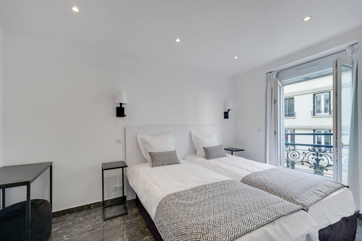Ein modernes Hotelzimmer mit einem großen Bett, zwei Nachttischen und Blick auf den Balkon.