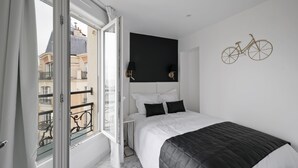 A modern bedroom with a large bed, a black headboard, and a bicycle decoration on the wall.