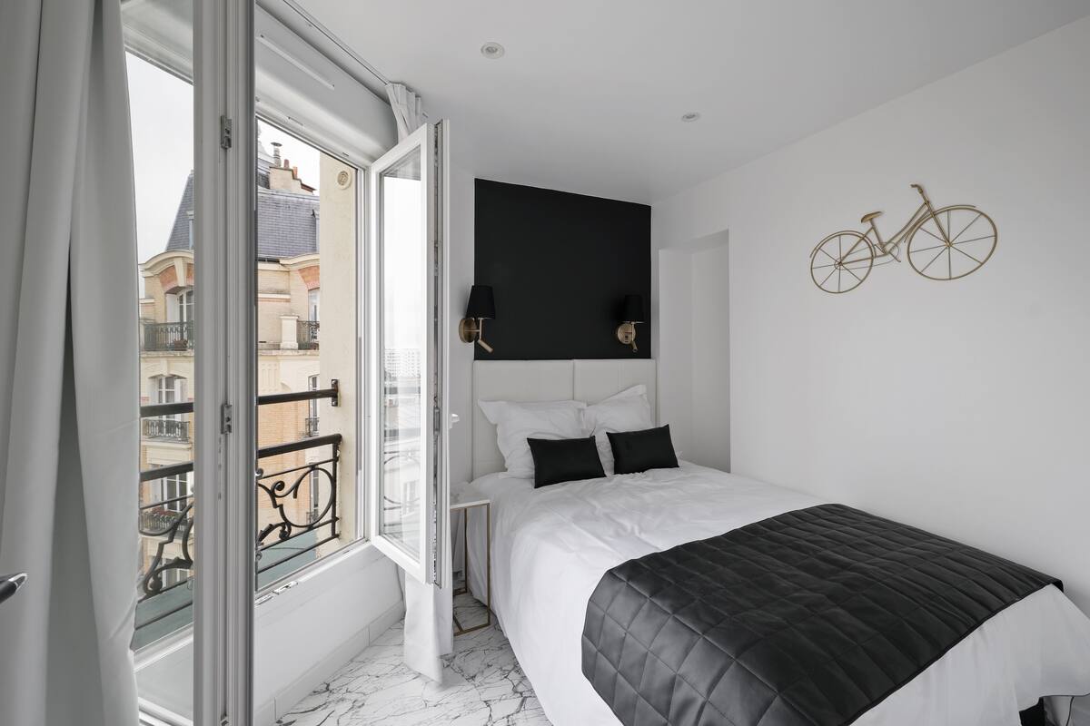 Ein modernes Schlafzimmer mit einem großen Bett, einem schwarzen Kopfteil und einer Fahrrad-Dekoration an der Wand.