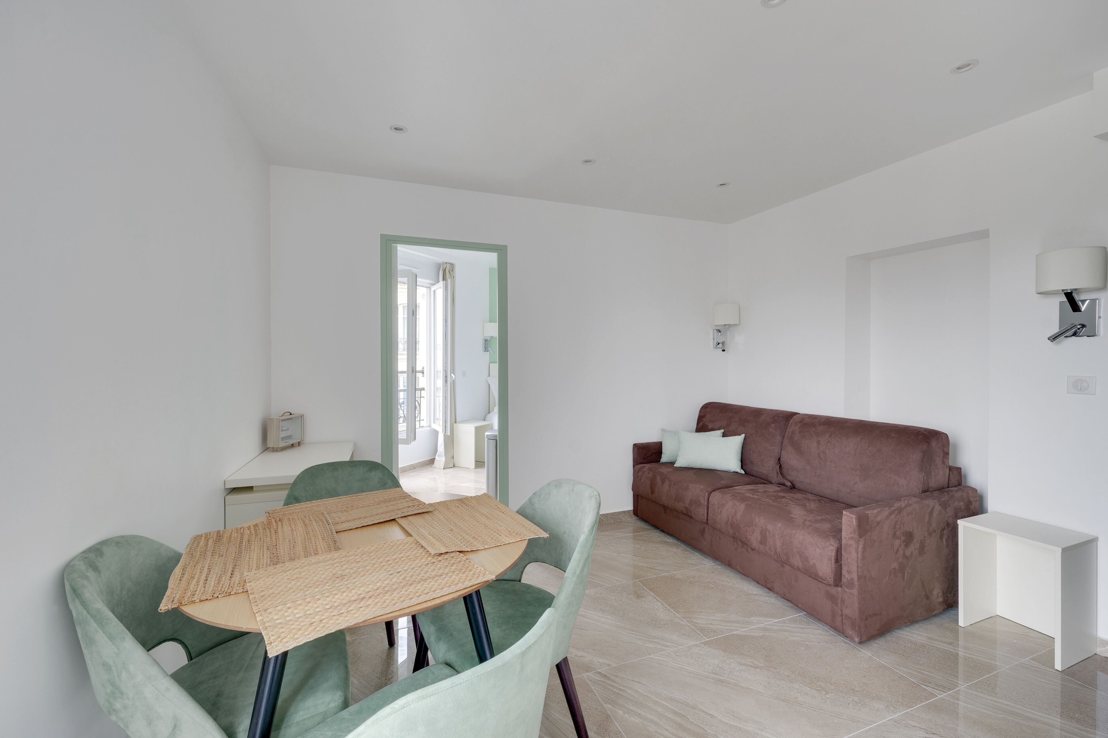 Een moderne woonkamer met een bruine bank, een groene fauteuil en een witte salontafel.