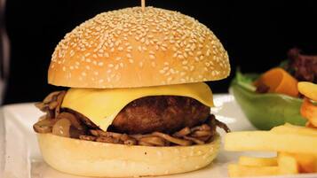 A hamburger with a sesame seed bun, cheese, and a beef patty, served with fries and a side salad.