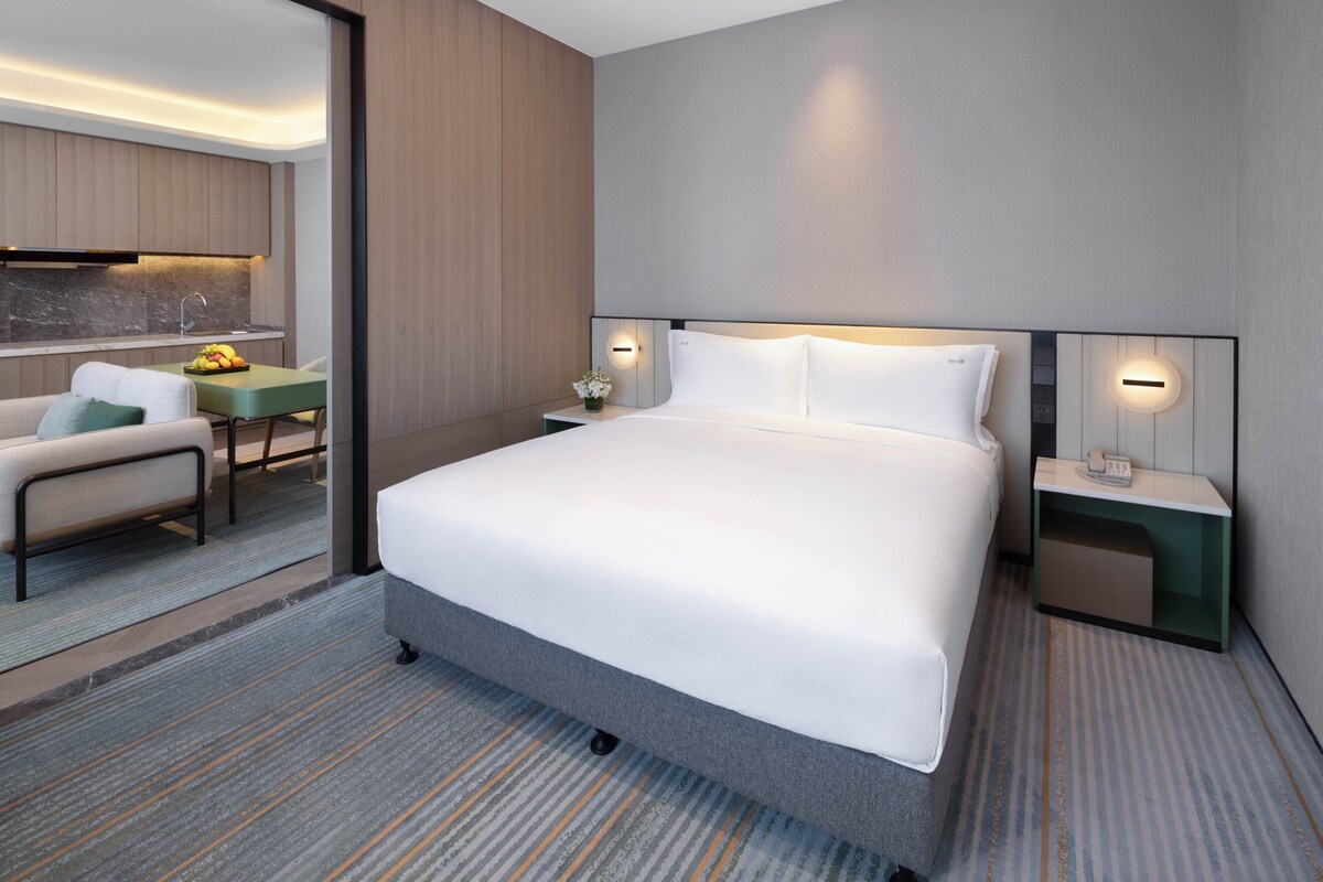 A hotel room with a large bed, a desk, and a chair.