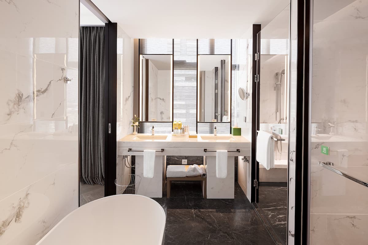 A modern bathroom with a marble vanity, a large mirror, and a separate shower area.
