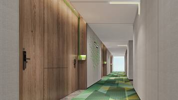 A corridor with wooden panel walls, a patterned floor, and recessed lighting.